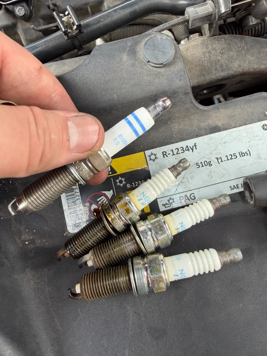 An old spark plug next to a new one